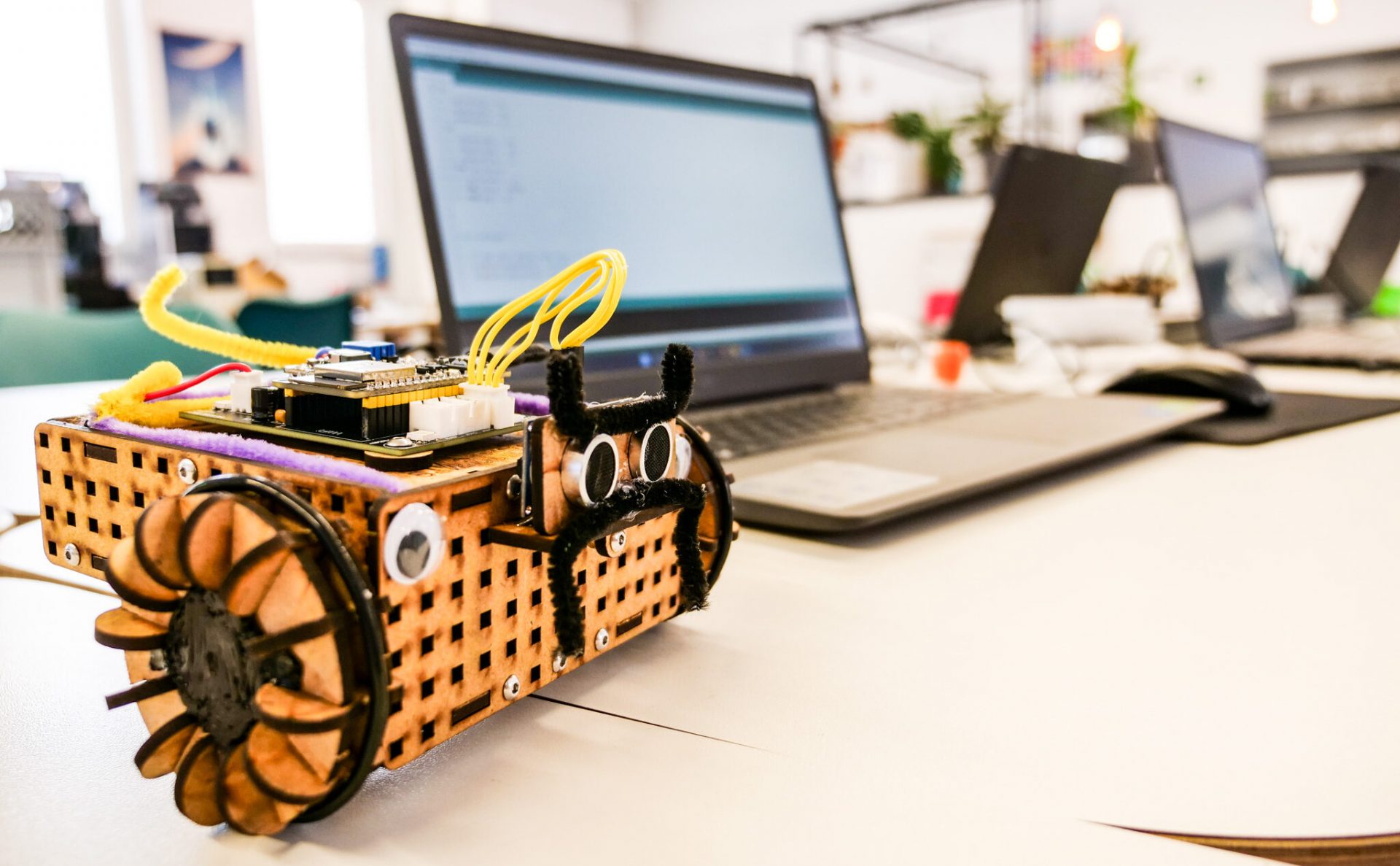 Selbstgebautes Robotik-Fahrzeug mit Elektronik vor einem Laptop